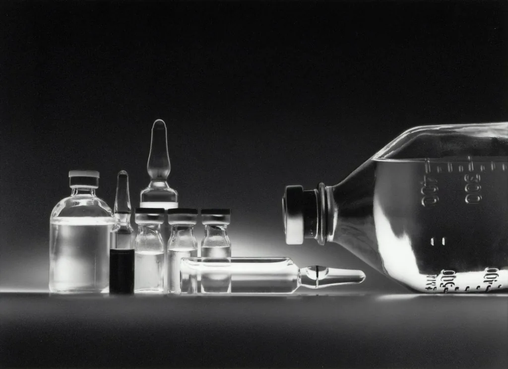Medical glass vials and infusion containers on a dark background